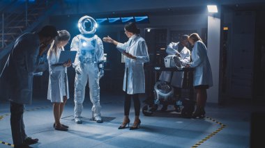 Uzay Mühendisleri Ekibi Galaksi Keşfi ve Seyahat İçin Yeni Uzay Giysileri Tasarladı. Beyaz önlük giyen bir grup bilim adamı tartışır, bilgisayar kullanır. Astronot Miğferi Yapılıyor
