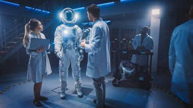 Beyaz Önlük Giyen Uzay Bilimadamları ve Mühendisleri Ekibi, Bilgisayarları kullanın, Yeni Uzay Giysileri İçin Astronot Miğferi İnşa Edin, Keşif ve Seyahat İçin Uyarlandı.