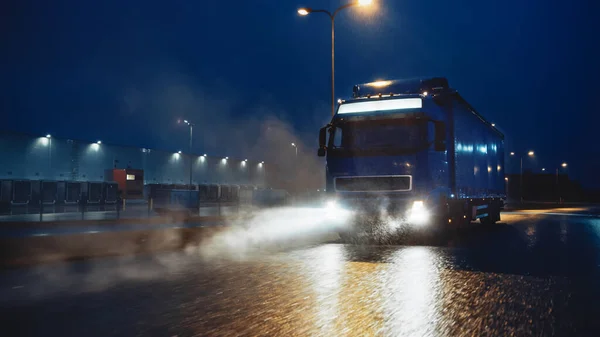 Blue Long Haul Semi-Truck with Cargo Trailer Full of Goods Travels At Night on the Freeway Road, Driving Across Continent Through Rain, Fog, Snow. 공업용 창고 지역. — 스톡 사진