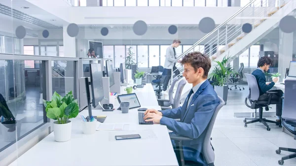 Nuori komea johtaja yllään puku ja solmio Keskustelut Työ hänen henkilökohtainen pöytätietokone. Monipuolinen ja motivoitunut liikemiehet Työskentele tietokoneiden Modern Open Office. — kuvapankkivalokuva