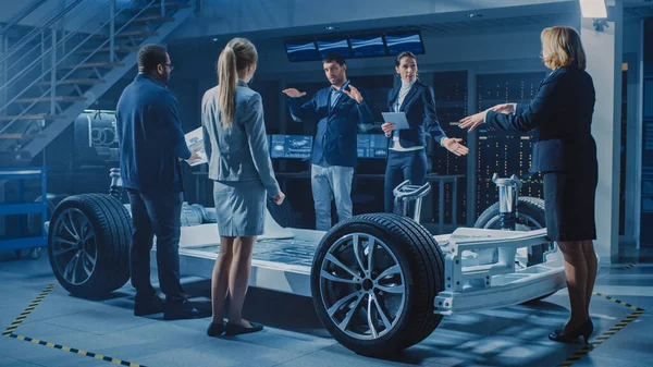 Снимок международной команды инженеров по автомобильному проектированию, представляющей шасси футуристической автономной электромобильной платформы группе инвесторов и предпринимателей. — стоковое фото