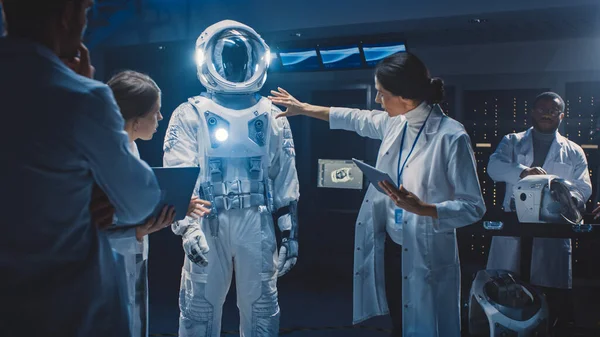 Olika team av flyg- och rymdforskare och ingenjörer bär vita rockar har Diskussion, Använd datorer Design New Space Suit Anpassad för Galaxy Exploration och resor. Konstruera Astronaut kostym — Stockfoto