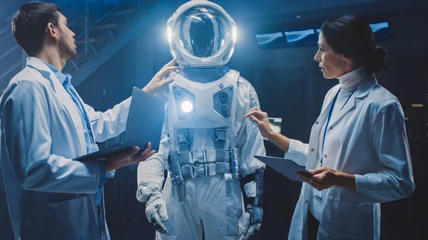 Diverse Team of Aerospace Engineers Design New Space Suit Anpassad för Galaxy Exploration och resor. Grupp av forskare bär vita rockar har diskussion, använda datorer. Konstruera Astronaut kostym — Stockfoto