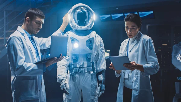 Változatos csapat űrkutató tudósok és mérnökök viselő fehér köpenyt van vita, Számítógépek használata, Tervezés új űrruha adaptált Galaxy Exploration és utazási. Űrhajós öltöny építése — Stock Fotó