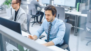 Yakışıklı Motivasyonlu Ofis İşçisi Masaüstü Bilgisayarı Kullanıyor, Klavyede Yazıyor. Güvenilir ve Genç İşadamı Profesyonel Ekip ile Büyük Parlak Ofiste Çalışıyor