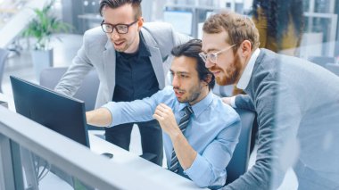 Parlak Modern Ofis 'te: İşadamı Masaüstü Bilgisayarında Oturuyor ve Çalışıyor, Proje Yöneticisi ve Takım Lideri Onun Yanında Duruyor. Tartışıyorlar, Problem Çözümünü Buluyorlar, Ekranı Gösteriyorlar