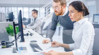 Güzel İş Kadını Masaüstü Bilgisayarı Kullanıyor, Proje Yöneticisine Grafik ve İstatistiklerle Belgeler Hakkında Danışmanlık Yapıyor. Arkaplanda Büyük Şirket Ofisinde.