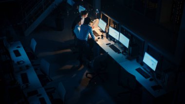 Modern Ofiste Gece Geç Saatler: Başarılı İş Adamları ve İş Kadınlarından oluşan Çeşitli Ekip Bilgisayar Etrafında Toplanıyor, Tartışıyor, Problem Çözümünü Buluyor, Projeyi Birlikte Tamamlıyor. Yüksek Açı