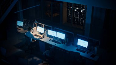 Ofiste Geç Saatlere Kadar Çalışmak: İşadamı Masaüstü Bilgisayarı Kullanıyor, Analiz Ediyor, Belgeleri Kullanıyor, Sorunları Çözüyor, Projeyi Bitiyor. Yüksek Açı Atışı