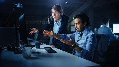 Kendine Güvenen İşadamı Masaüstü Bilgisayarı Kullanıyor, Kadın Yöneticisi Özel Görevleri, Muhasebe ve Stratejiyi Açıklıyor. Gece geç saatlerde kurumsal ofiste tartışan ve tartışan profesyonel insanlar..