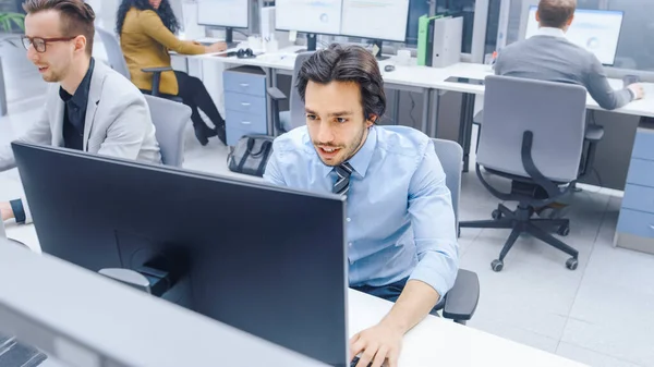 Handsome Motivated Office Worker 는 데스크톱 컴퓨터를 사용하여 키 보드에 타이핑 한다. 신임받는 젊은 사업가와 전문가 팀과 함께 빅 브라이트 사무실에서 일하다 — 스톡 사진