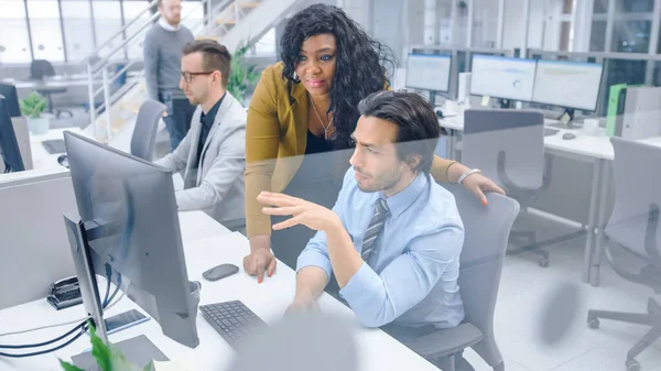 In Bright Modern Office: Handsome Office Worker sitting and Working at His Desktop Computer, Discusses Problem Solution with His Female Project Manager ( 영어 ) 공식 웹 사이트. 다양 한 사업가들로 이루어진 팀이 문제를 해결하다 — 스톡 사진