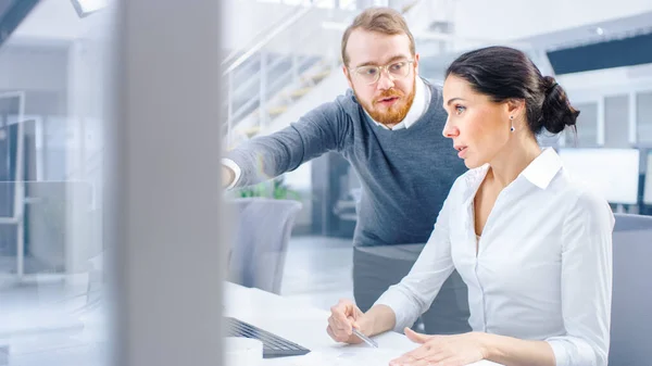 Schöne Geschäftsfrau verwendet Desktop-Computer, berät ihren Projektleiter über Dokumente mit Grafiken und Statistiken. Im Hintergrund Großunternehmen — Stockfoto