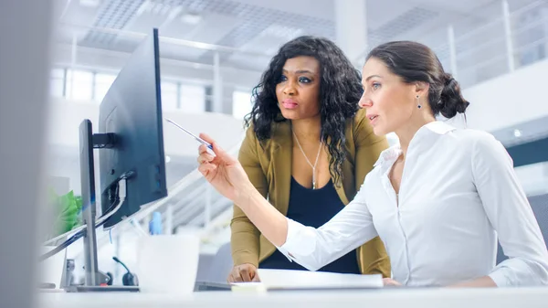 No escritório moderno brilhante: Mulher de negócios bonita Sentado e trabalhando em seu computador desktop com gerente de projeto em pé ao lado dela, Eles têm discussão, encontrar solução de problema — Fotografia de Stock