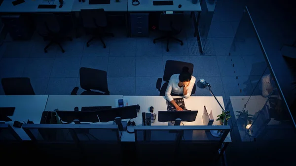 Trabajar hasta altas horas de la noche en la oficina: Empresaria usando computadora de escritorio, analizando, usando documentos, resolviendo problemas, terminando el proyecto. Disparo de ángulo alto — Foto de Stock