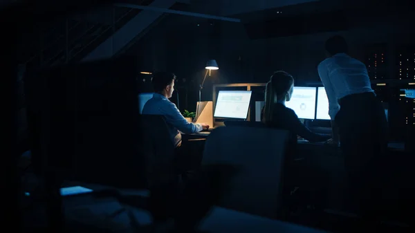 Tarde da noite no escritório moderno: Equipe diversa de empresários de sucesso e mulheres de negócios trabalham em computadores desktop, tendo discussão, encontrando soluções para problemas, projeto de acabamento — Fotografia de Stock