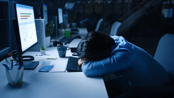 In the Office at Night Overworked Tired Office Worker Uses Desktop Computer but Falls Asleep Fast. Tired Exhausted Businessman Falls asleep at His Job