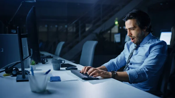 In ufficio di notte affaticato lavoratore ufficio utilizza Desktop Computer sbadiglio, bevande caffè. Stanco esausto uomo d'affari Finitura Progetto importante — Foto Stock