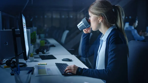 Praca do późna w nocy w biurze: Bizneswoman Korzystanie z komputera stacjonarnego i picia kawy, Analizowanie, Korzystanie z dokumentów, Rozwiązywanie problemów, Zakończenie projektu. — Zdjęcie stockowe