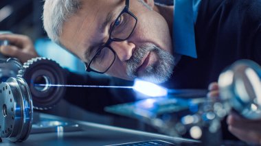 Gözlüklü Odaklanmış Orta Çağ Mühendisi 'nin Yakın plan Portresi Yüksek Hassas Lazer Ekipmanı, Mercek ve Optik Elektronik Kullanımı. Süper iletken materyali test ediliyor 