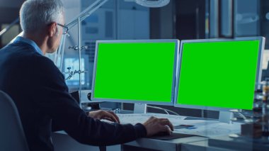 İki Yeşil Model Senaryoyla Profesyonel Mühendis Bilgisayarda Çalışıyor. Arka plan Endüstriyel Elektronik Tasarım Ajansı 'nda. Omzunun üstünden.