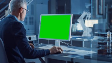 Profesyonel Ağır Sanayi Mühendisi Green Mock-up Bilgisayar 'da çalışıyor. Çeşitli Robot, Mimari ve Makine Bileşenlerine sahip Mühendislik Bürosu ve Endüstriyel Tasarım Ajansı