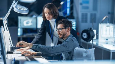 Gelecekçi Makine Geliştirme Mühendisi Masasında Bilgisayar Çalışıyor, Kadın Proje Yöneticisi ile Konuşuyor. Modern Endüstriyel Tasarım Kurumu 'nda çalışan Profesyonel Ekip