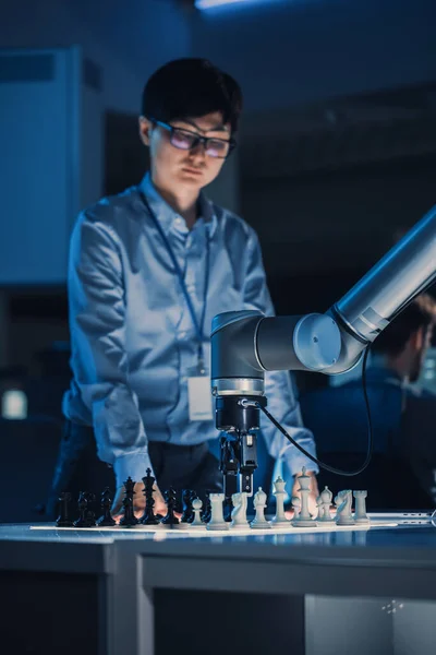 Вертикальний знімок професійного японського інженера-розробника, який випробовує штучний інтелект, граючи в шахи з футуристичною робототехнічною рукою. Лабораторія сучасних досліджень високих технологій . — стокове фото