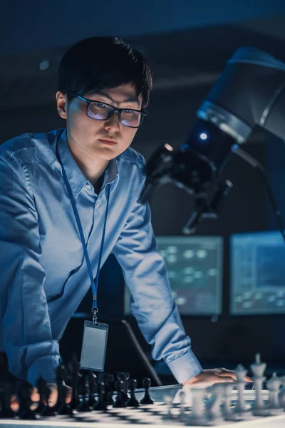 Vertical Shot of a Professional Japanese Development Engineer Testing an Artificial Intelligence Interface by Playing Chess with a Futuristic Robotic Arm. 공식 웹 사이트. 첨단 기술 현대 연구소. — 스톡 사진