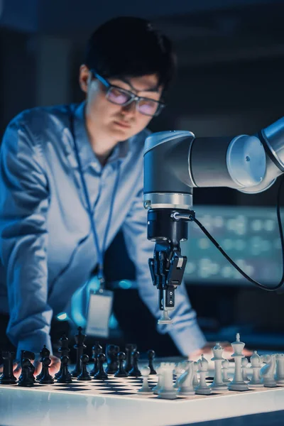 Κάθετη βολή ενός επαγγελματία Ιάπωνα μηχανικό ανάπτυξης Δοκιμάζοντας μια διεπαφή τεχνητής νοημοσύνης παίζοντας σκάκι με ένα φουτουριστικό ρομποτικό βραχίονα. Εργαστήριο Σύγχρονης Έρευνας Υψηλής Τεχνολογίας. — Φωτογραφία Αρχείου