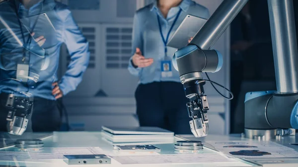 Futuristic Artificial Intelligence Robotic Arm Operates and Moves a Metal Object, Picks It Up or Puts it Down under Technician Control. High Tech Research Laboratory with Modern Equipment.