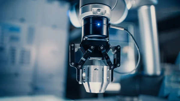 Primer plano de un brazo robótico futurista moviendo un objeto metálico y colocándolo. El equipo de ingenieros observa este proceso avanzado. Están en un laboratorio de investigación de alta tecnología con equipos modernos. — Foto de Stock