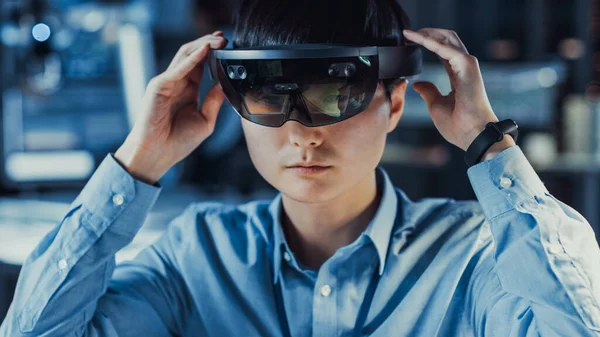 Ingegnere giapponese professionista di sviluppo di elettronica in camicia blu sta indossando un auricolare di realtà virtuale e guardando intorno al laboratorio di ricerca high-tech con moderne attrezzature informatiche. — Foto Stock