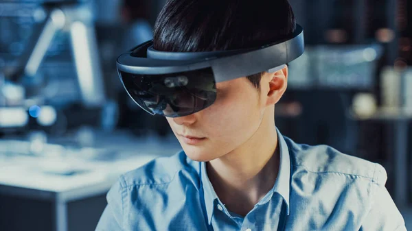 Engenheiro de desenvolvimento de eletrônica japonês profissional em camisa azul está vestindo um fone de ouvido de realidade virtual e olhando ao redor do laboratório de pesquisa de alta tecnologia com equipamentos de computador modernos. — Fotografia de Stock