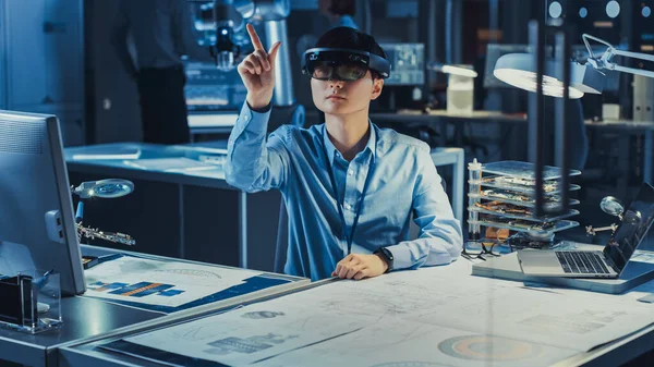 Professional Japanese Development Engineer travaille dans un casque AR, faisant des gestes de toucher des pièces graphiques virtuelles dans le laboratoire de recherche de haute technologie avec du matériel informatique moderne. — Photo