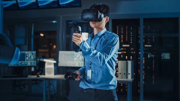 Professzionális japán fejlesztő mérnök kék ingben használ kiterjesztett valóság headset és Joysticks egy high-tech kutató laboratóriumban modern berendezésekkel. — Stock Fotó