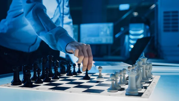 Gros plan sur une intelligence artificielle utilisant un bras robotique futuriste dans un jeu d'échecs contre un humain. Robot déplace un pion. Ils sont dans un laboratoire de recherche moderne de haute technologie. — Photo