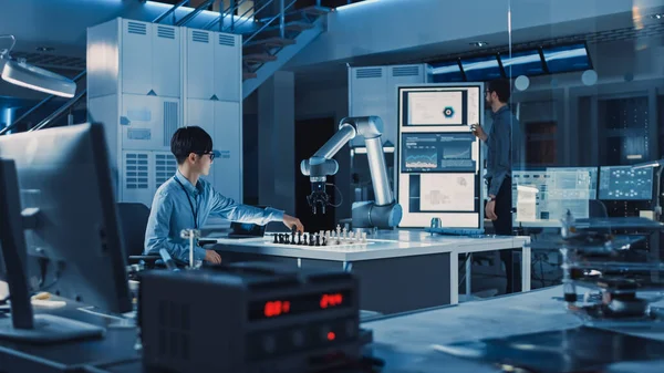 Ingeniero de Desarrollo Japonés Profesional está Probando una Interfaz de Inteligencia Artificial Jugando Ajedrez con un Brazo Robótico Futurista. Están en un Laboratorio de Investigación Moderna de Alta Tecnología. —  Fotos de Stock
