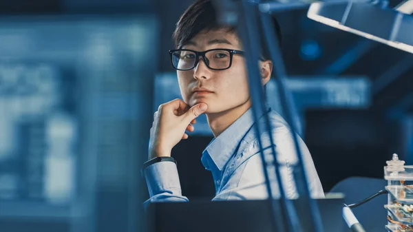 Muotokuva vakava ammatillinen japanilainen kehitysinsinööri ajattelu työpaikallaan korkean teknologian tutkimuslaboratoriossa nykyaikaisilla tietokonelaitteilla. — kuvapankkivalokuva