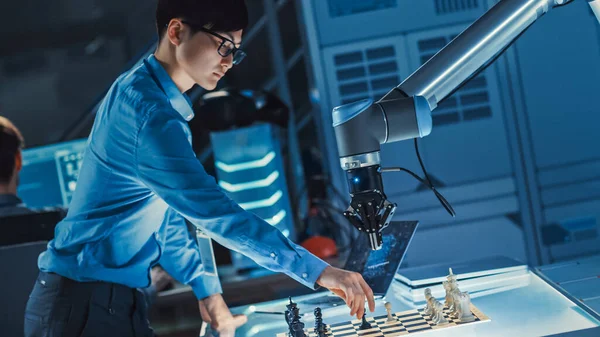 Ingeniero de Desarrollo Japonés Profesional está Probando una Interfaz de Inteligencia Artificial Jugando Ajedrez con un Brazo Robótico Futurista. Están en un Laboratorio de Investigación Moderna de Alta Tecnología. —  Fotos de Stock