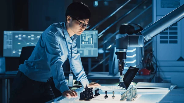 Professional Japanese Development Engineer sta testando un'interfaccia di intelligenza artificiale giocando a scacchi con un braccio robotico futuristico. Sono in un laboratorio di ricerca moderna ad alta tecnologia. — Foto Stock