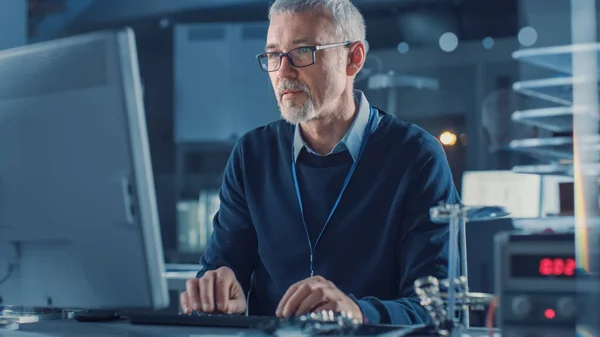 Ingeniero de Reparación de Electrónica de Edad Media Trabajando en Ordenador Personal en su Taller, Chequea Placa Madre. En el fondo varias placas de circuitos, dispositivos de alta tecnología, dispositivos y componentes — Foto de Stock