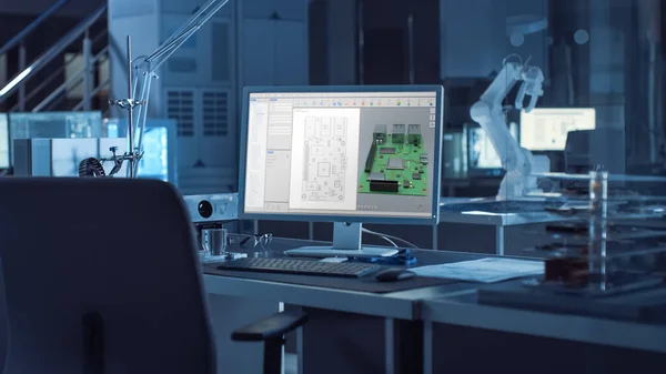 Op de bureaucomputer met CAD-software en ontwerp van 3D-componenten voor industriële machines. In de achtergrond Robot Arm Concept Staande in Zwaar Donker. Industriële ingenieursfaciliteit. — Stockfoto