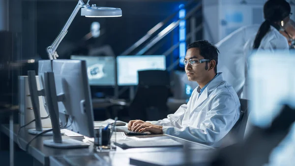 Male IT Scientist utiliza el programa de monitoreo y control de sistemas de visualización de computadoras. En el Laboratorio de Desarrollo Tecnológico de Antecedentes con Científicos, Ingenieros trabajando — Foto de Stock