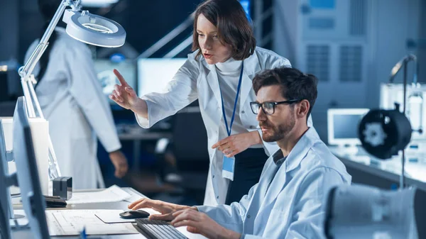 Engenheira de Desenvolvimento de Máquinas Trabalhando no Computador em Sua Mesa, Fala com o Gerente de Projetos Feminino. Equipe de Profissionais Trabalhando no Laboratório de Design Industrial Moderno — Fotografia de Stock