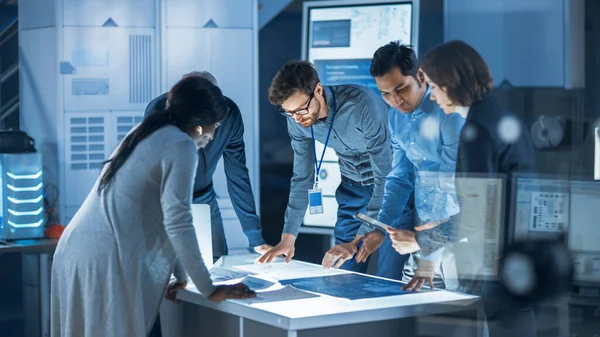 Engineers Meeting in Technology Research Laboratory: Engineers, Scientists and Developers Gathered Around Illuminated Conference Table, Talking and Finding Solution. Industrial Design Facility — Stock Photo, Image