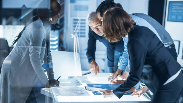 Reunião de Engenheiros em Laboratório de Pesquisa Tecnológica: Engenheiros, Cientistas e Desenvolvedores Reunidos em torno da Mesa de Conferências Iluminada, Solução de Conversação e Pesquisa, Inspeção e Análise — Fotografia de Stock