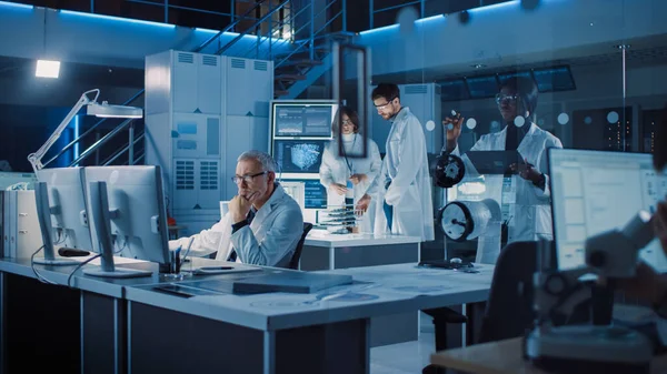 Diversi team internazionale di scienziati e ingegneri industriali che indossano camici bianchi che lavorano alla progettazione di macchinari industriali nel laboratorio di ricerca. Professionisti che utilizzano i computer e parlano — Foto Stock