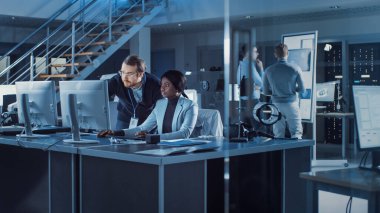 Elektronik Geliştirme Mühendisi Bilgisayar üzerinde çalışıyor, Proje Yöneticisi ile konuşuyor. Profesyonel Ekip Modern Endüstriyel Mühendislik için CAD Yazılım, Makine Öğrenme ve Sinirsel Ağ Kullan