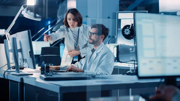 Ingeniero de desarrollo de motores de máquina Trabajando en la computadora en su escritorio, habla con el gerente de proyecto, muestra el componente de prototipo. Equipo de Profesionales Trabajando en el Laboratorio de Diseño Industrial Moderno — Foto de Stock